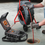 Technician performing a drain camera inspection using professional CCTV equipment to diagnose underground pipe blockages.